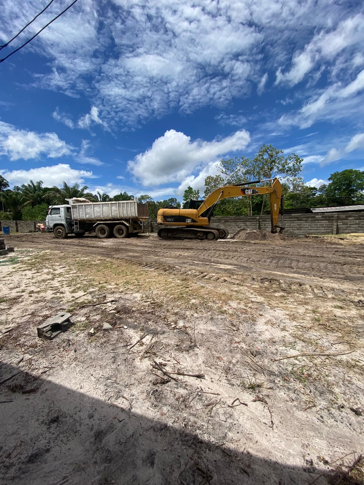 Escavadeira CAT e caminhão basculante em obra de terraplanagem da Collect em Manaus